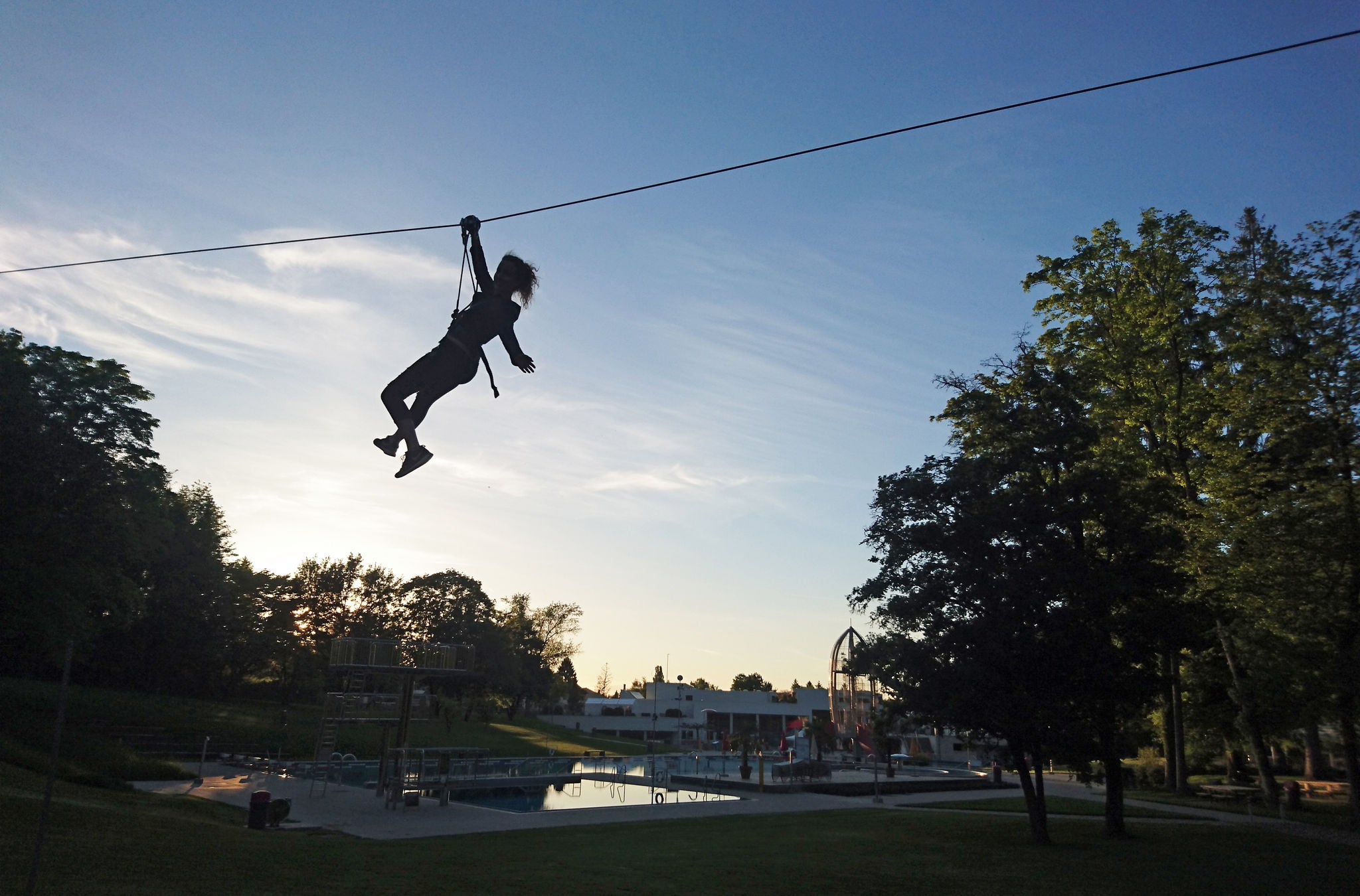 Frau bei Sonnenuntergang auf der Seilbahn im Seilpark Zürich