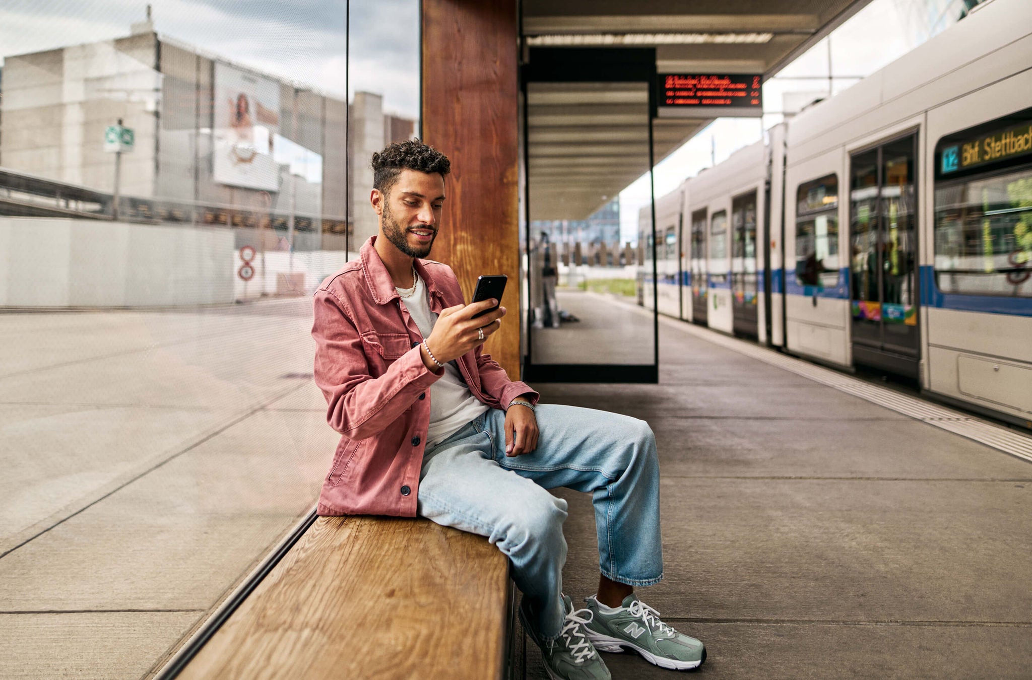 Ein junger Mann an der Haltestelle erneuert in der ZVV-App sein Abo.