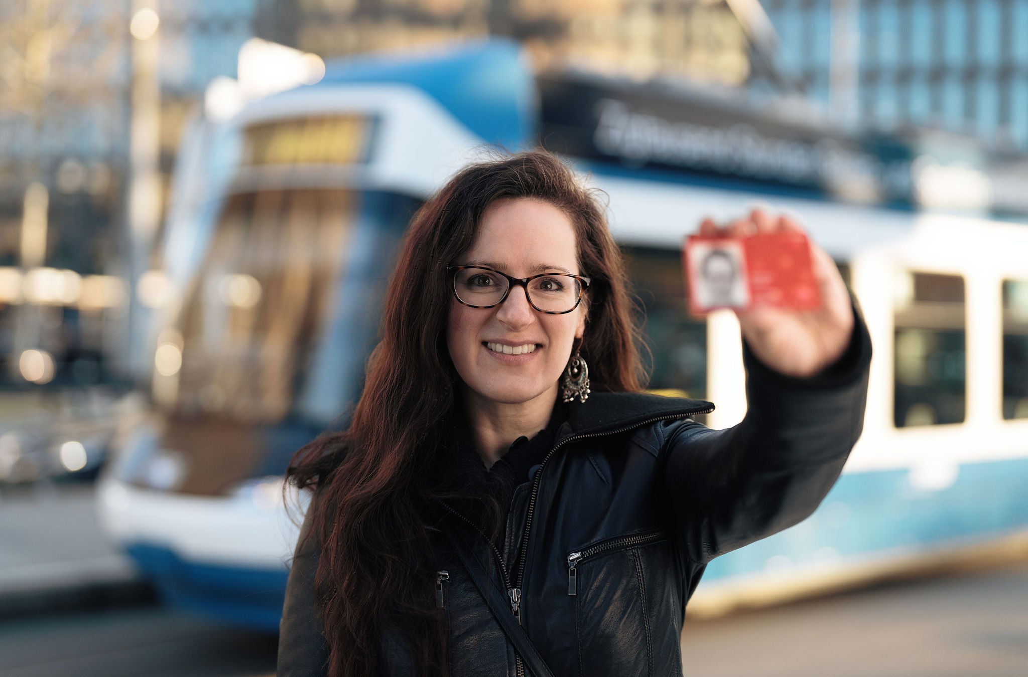 Junge Frau mit ZVV-Abo und Tram im Hintergrund