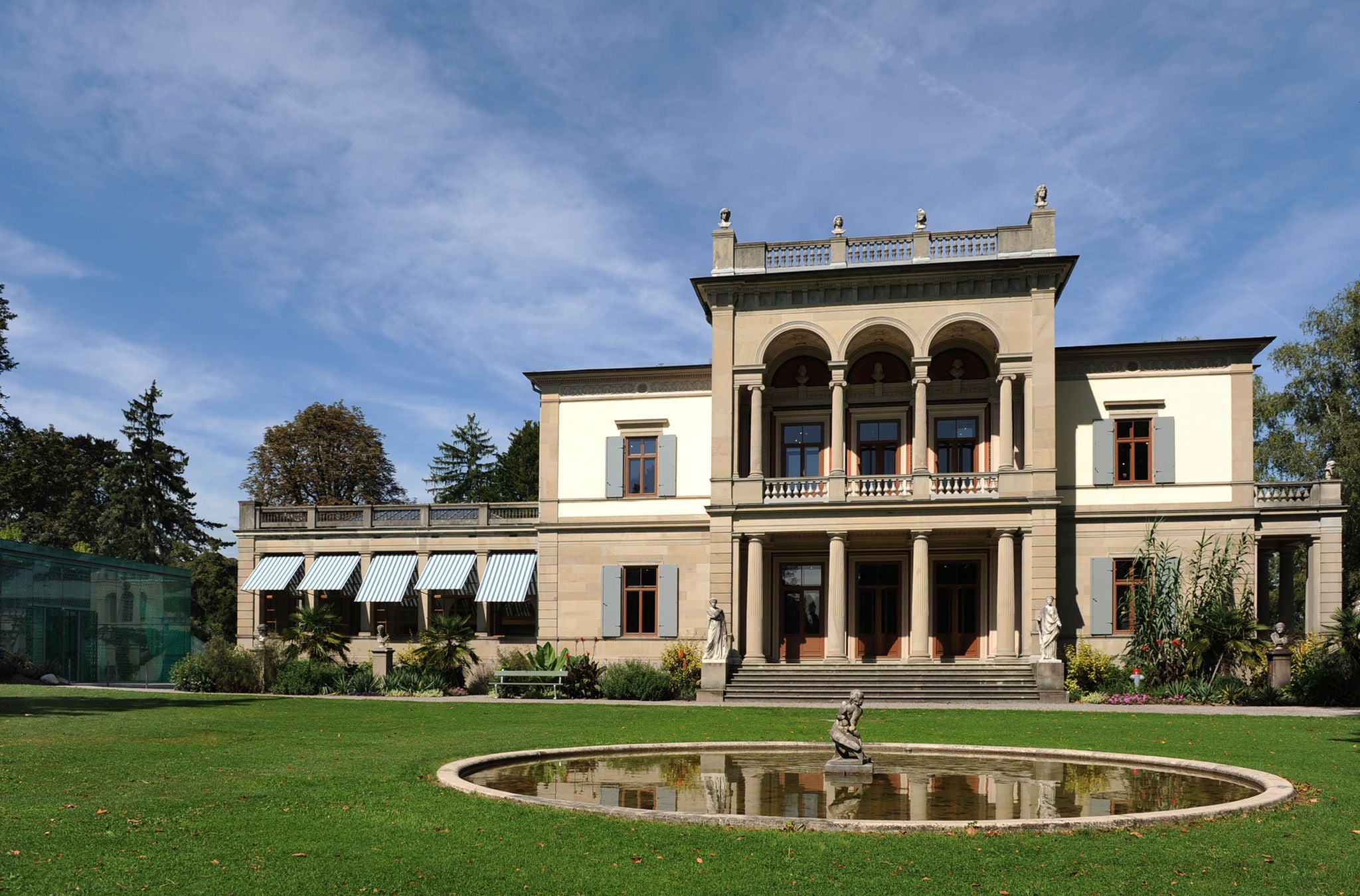 Aussenansicht des Museum Rietberg - eine historische Villa hinter einen Brunnen mit eines Skulptur.