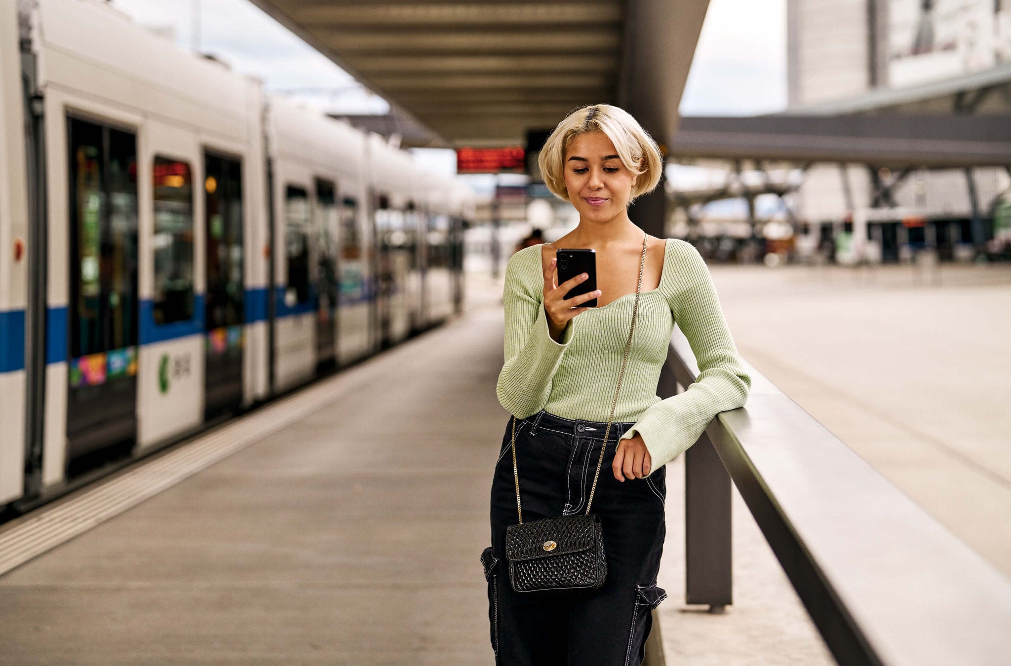 Einfacher Ticketkauf mit der ZVV-App Eine junge Frau steht an der Haltestelle und kauft sich ein ZVV-Ticket.