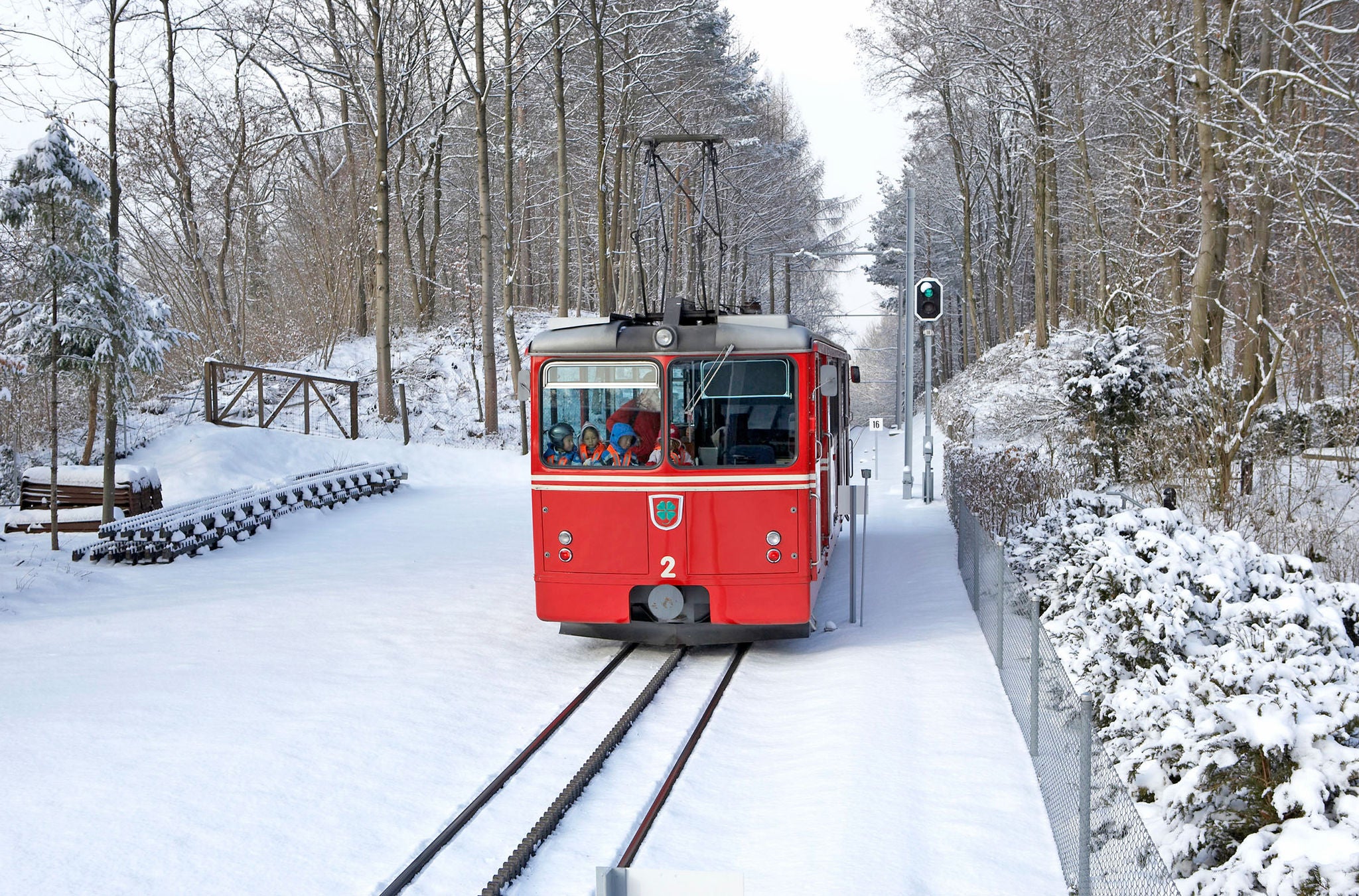 Die rote Dolderbahn fährt im Winter durch den Schnee. 