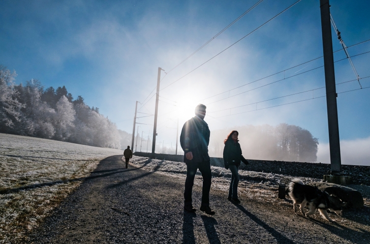 Frau und Mann mit Hund am Spazieren.